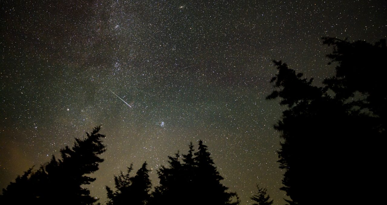 Bright Perseid meteors streak across a starry night sky, showcasing the annual meteor shower.