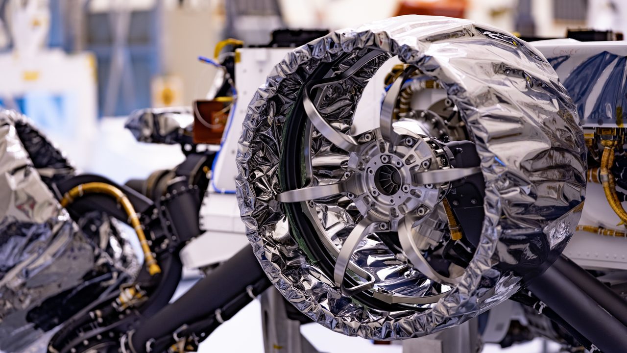 Close-up of Mars 2020 Perseverance Rover's durable wheels on rocky Martian terrain.