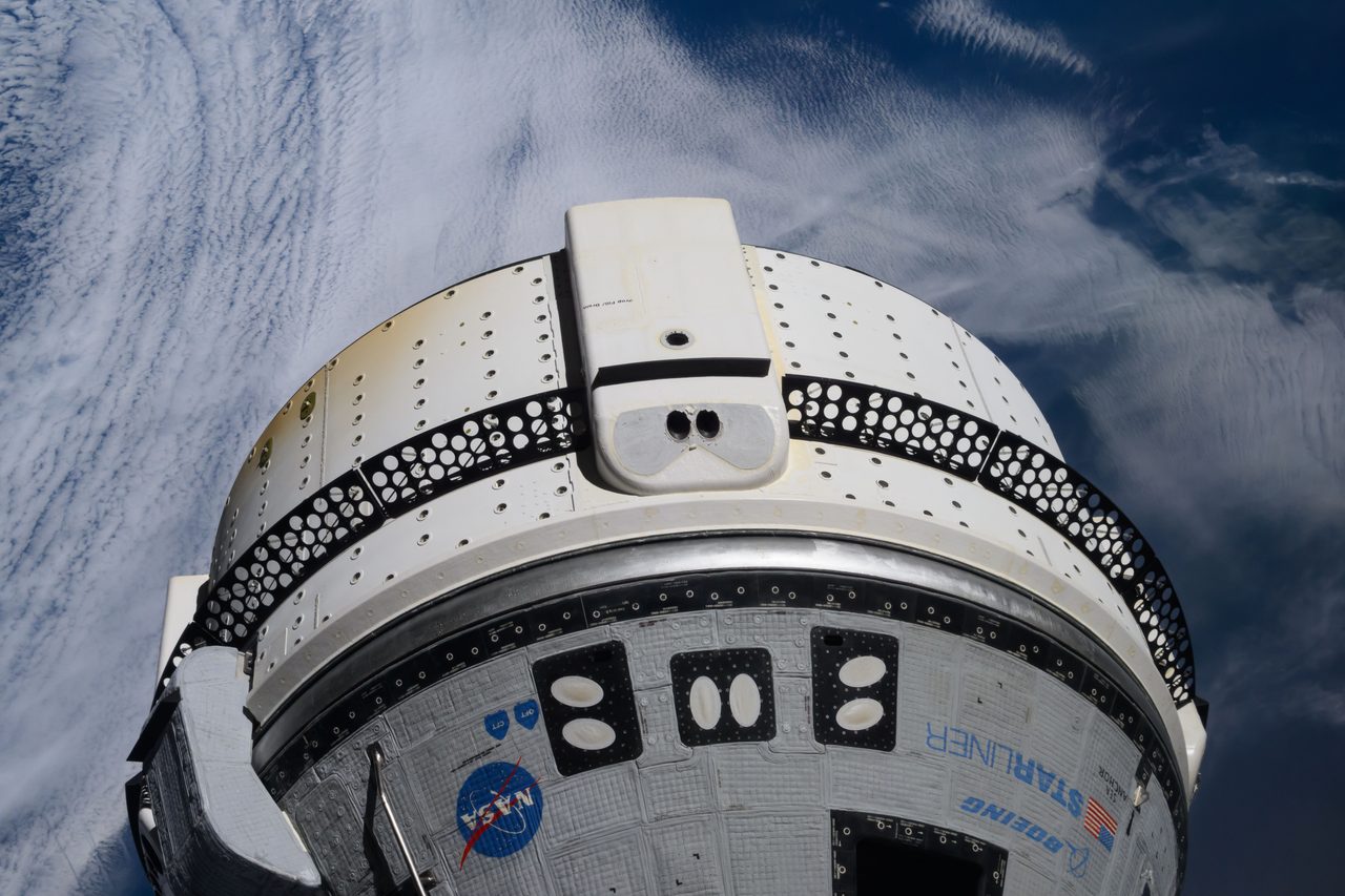Boeing's Starliner spacecraft docked at the International Space Station with Earth in the background.