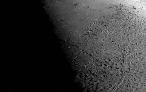 Simulated aerial journey over Neptune's moon Triton, showcasing its rugged terrain and icy surface.
