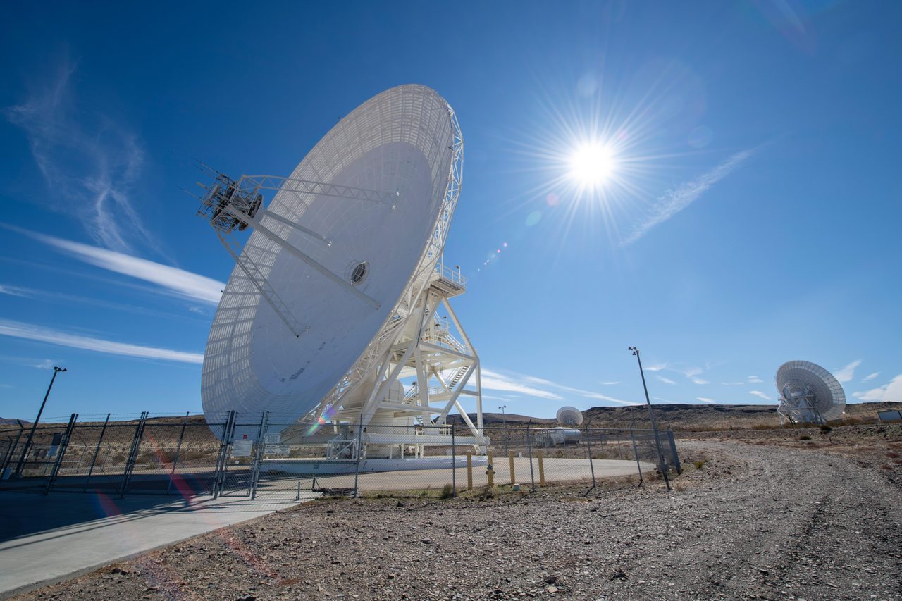Array of large antenna dishes at NASA's Goldstone Deep Space Network complex under clear blue sky.
