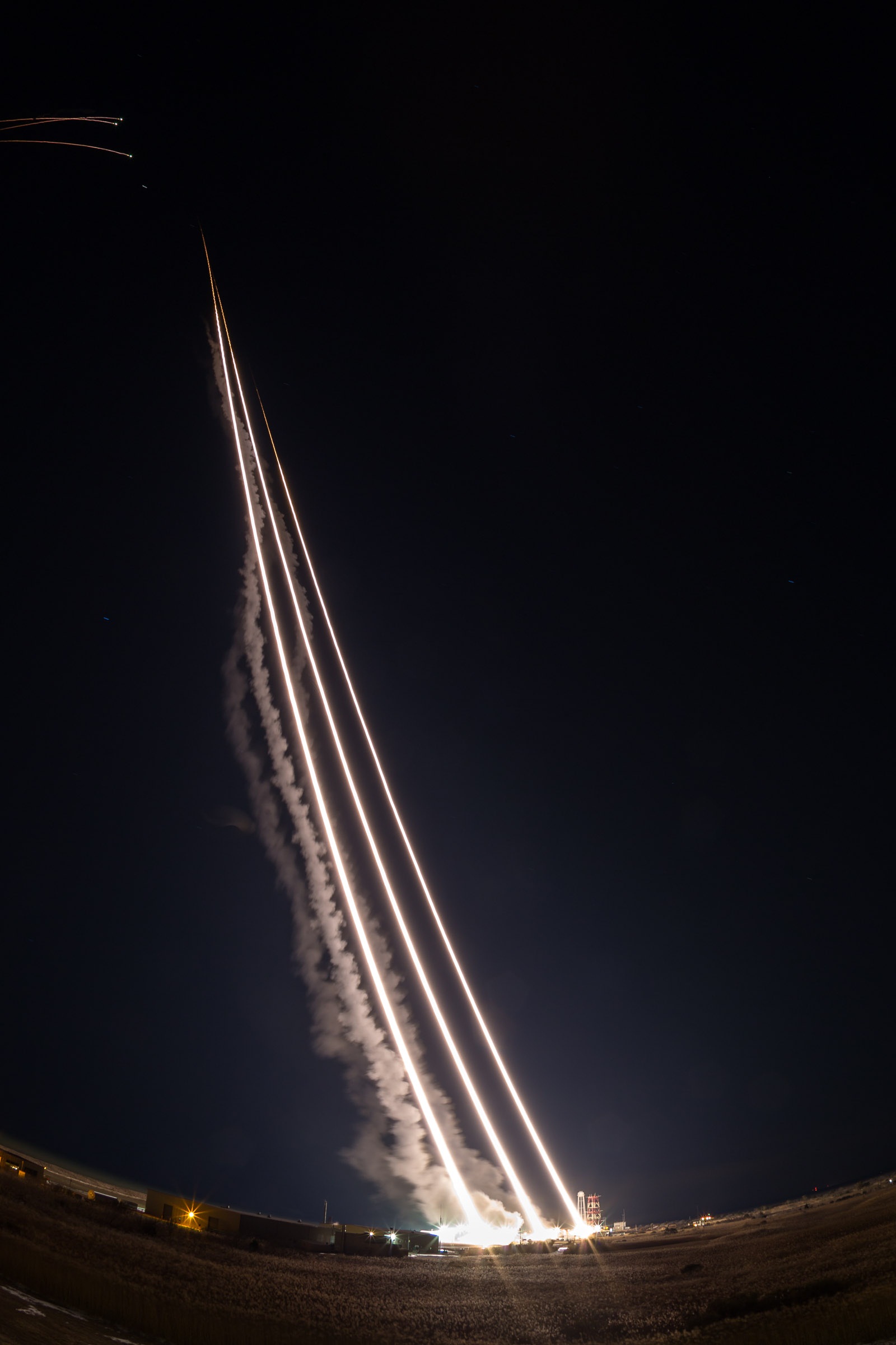 Multiple rockets launch into night sky from NASA's Wallops Flight Facility.