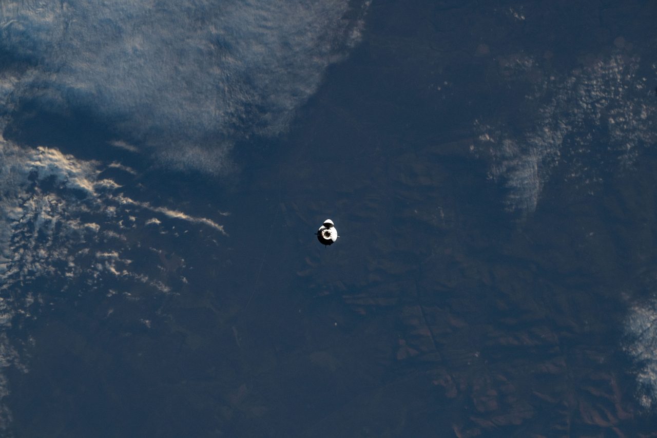 SpaceX Dragon spacecraft nearing the International Space Station with Earth in the background.