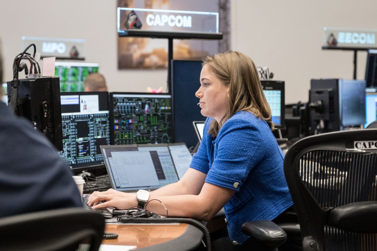 NASA engineer at control panel communicating with astronauts during space mission.