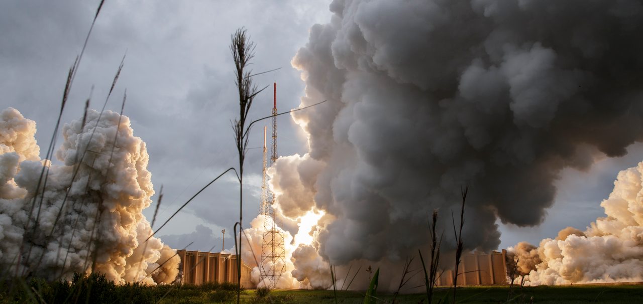 A rocket launches the James Webb Space Telescope into space, illuminating the night sky with fiery exhaust.