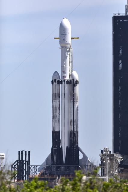 SpaceX Falcon Heavy rocket launching STP-2 mission into space with bright flames and smoke trail.