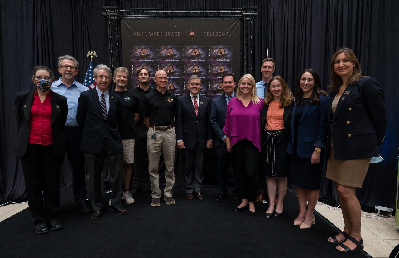 A group of people at the JWST Stamp Issuance Ceremony, with a large stamp image displayed.