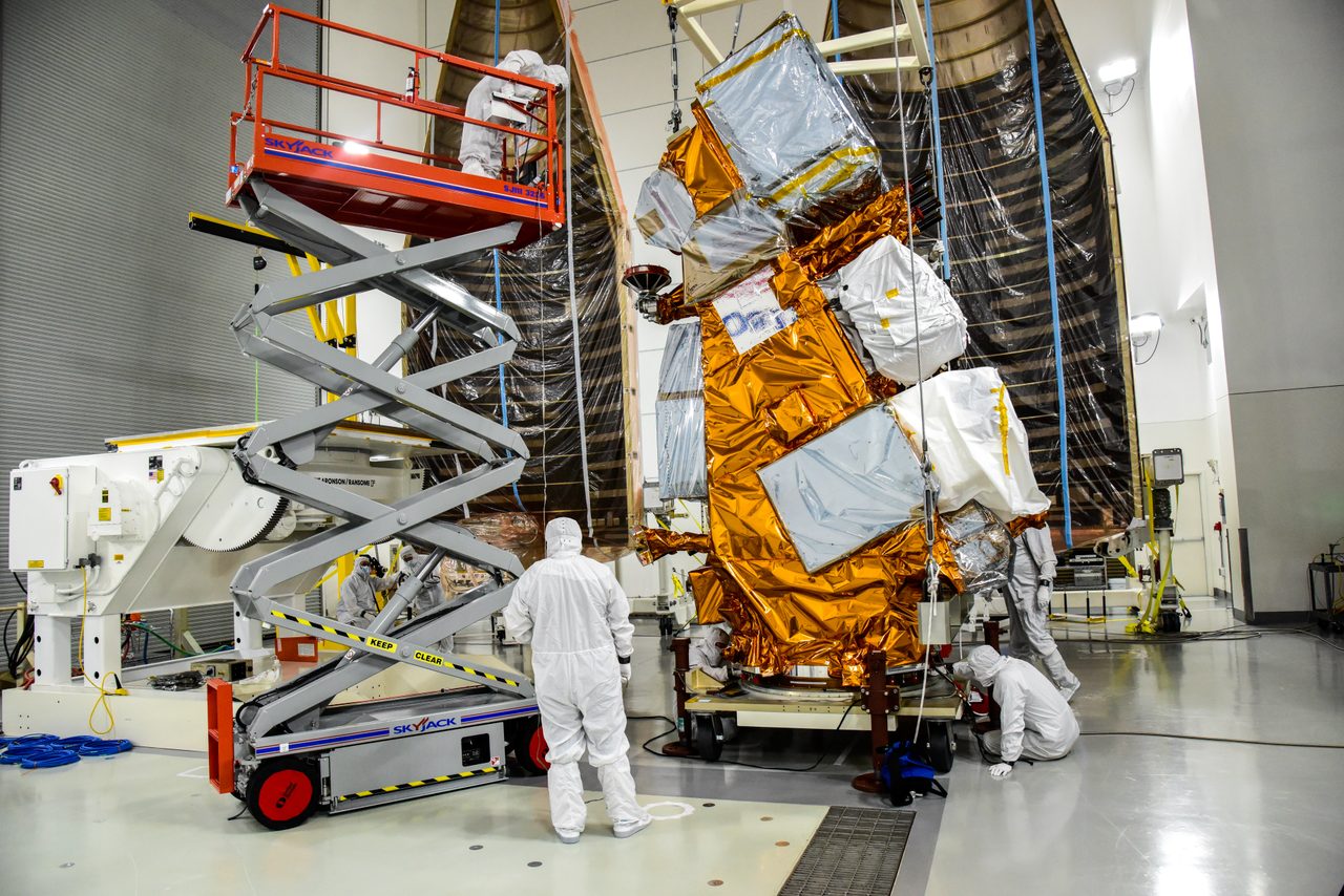 Technicians carefully move the JPSS-2 spacecraft onto an integration and testing cart inside a cleanroom.