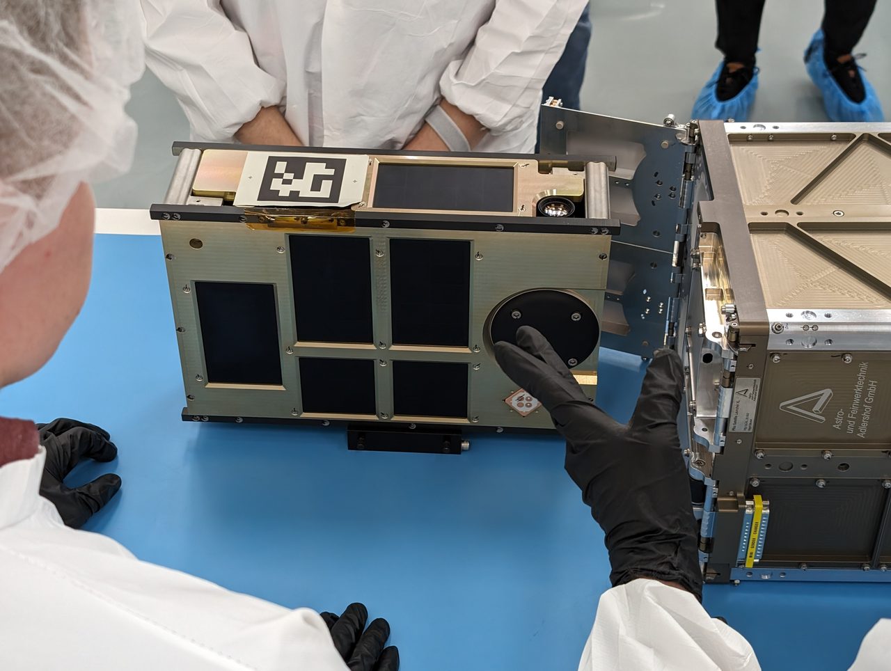Technicians in clean suits work on Firefly Demo-2 payload inside a sterile processing facility.