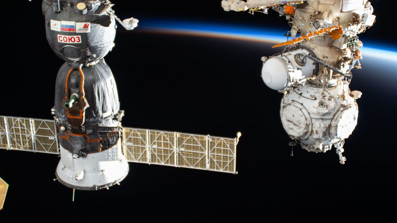 The International Space Station silhouetted against a vibrant sunset over China's landscape