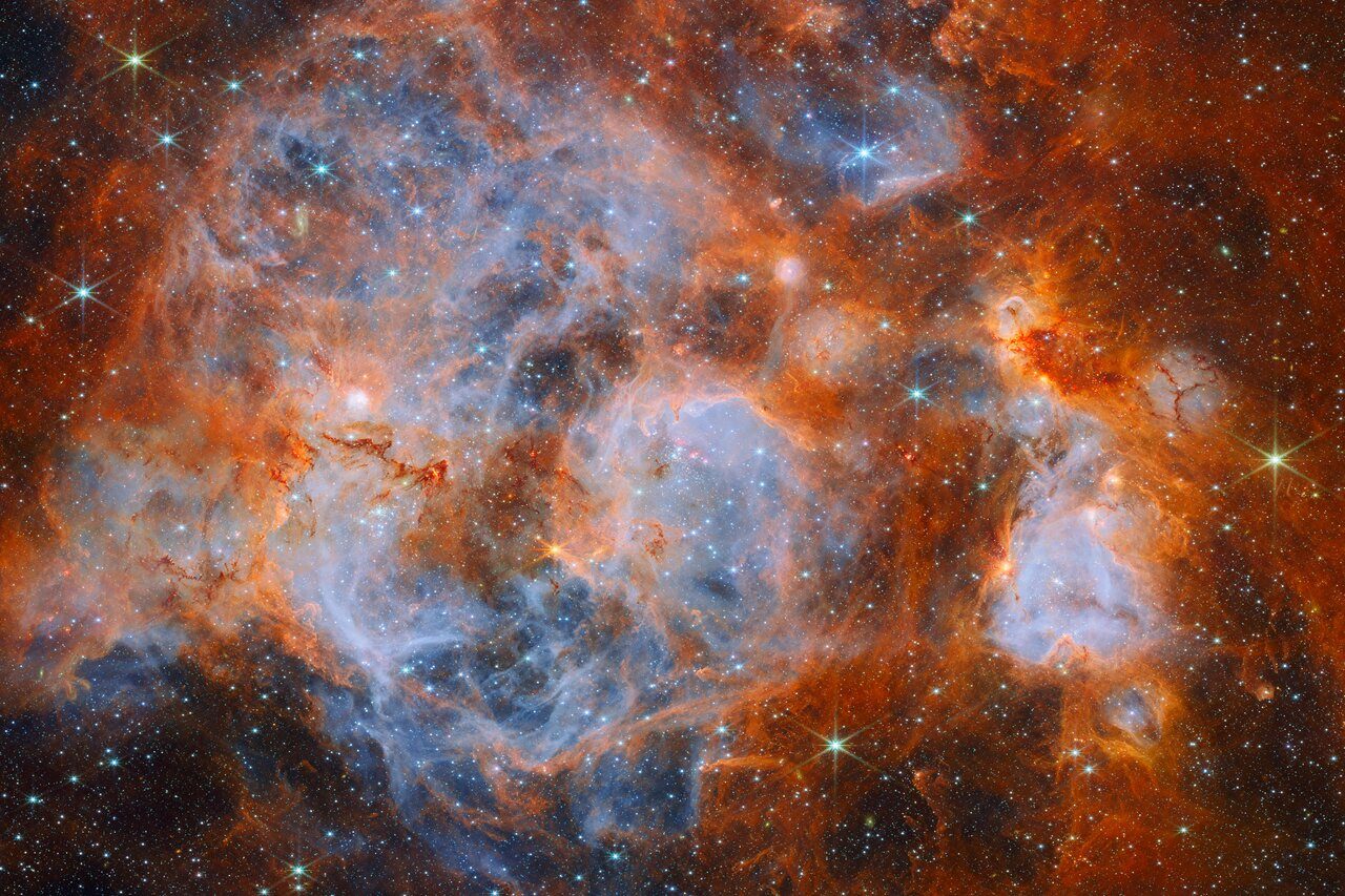 Bright stars forming within a colorful, swirling nebula in deep space.