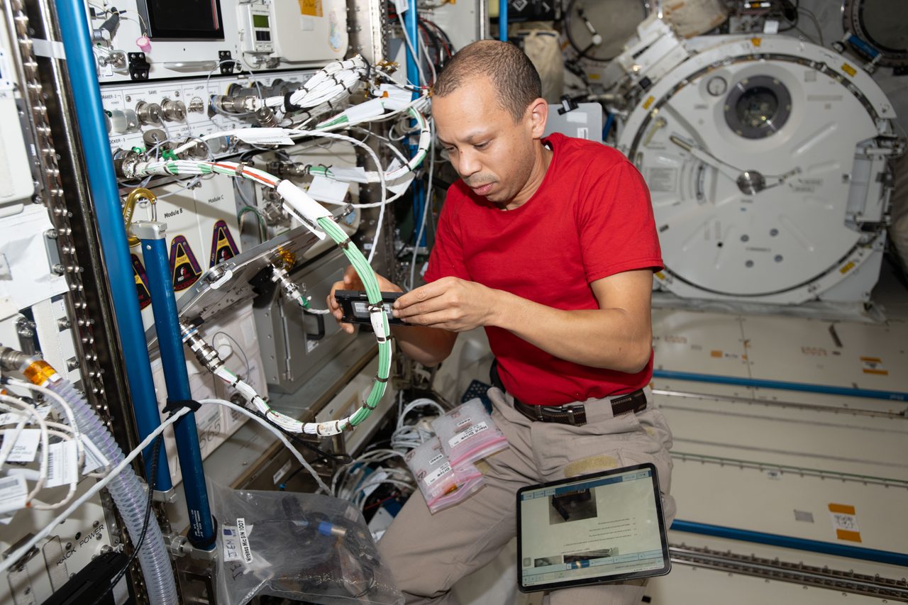 NASA astronaut Chris Williams carefully replaces computer parts inside a scientific device aboard the International Space Station.