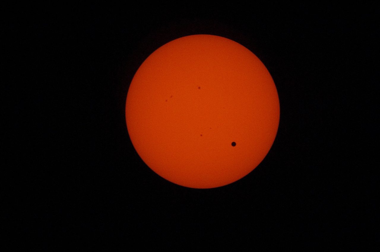 Detailed solar observation during Venus transit, showing sunspots and planetary silhouette.