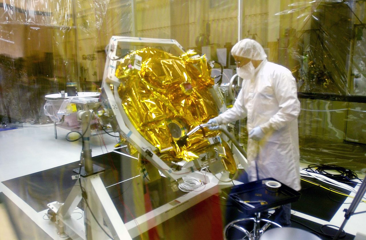Technicians attaching solar arrays to SciSat-1 satellite at Vandenberg Air Force Base for ozone research.