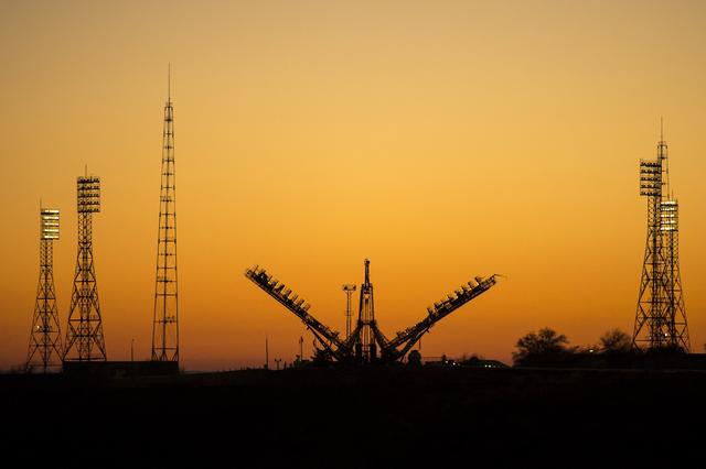 A Soyuz rocket is transported horizontally on a rail track under a clear blue sky during Expedition 38 rollout.