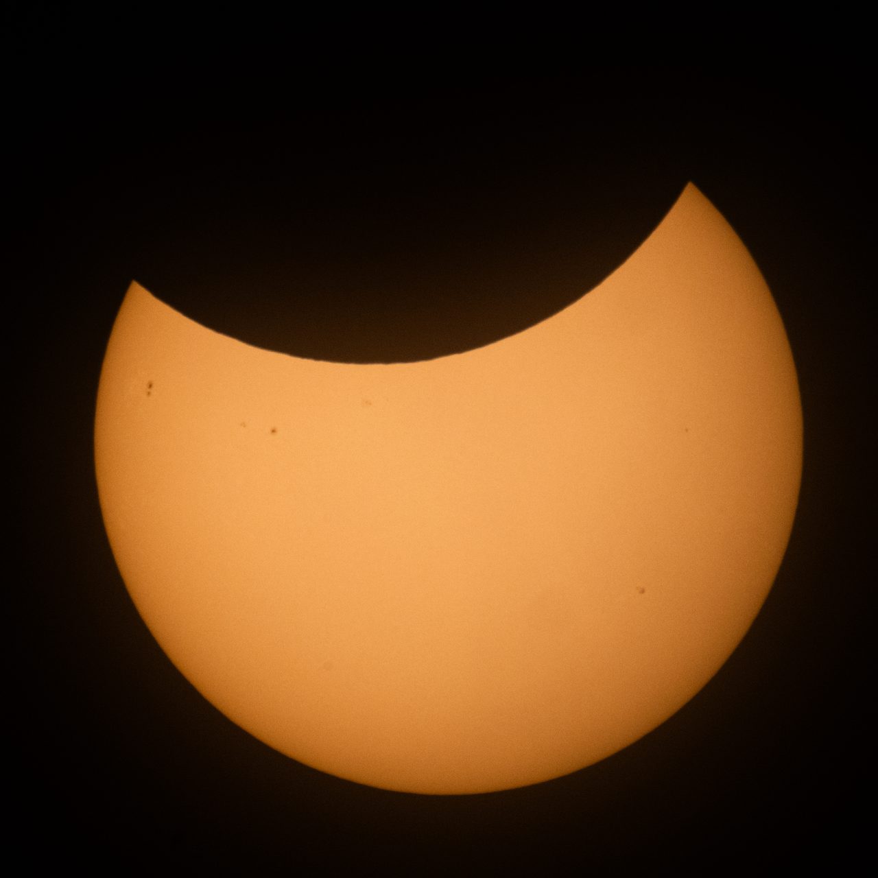 A partial solar eclipse with the sun partially obscured by the moon, creating a crescent shape.