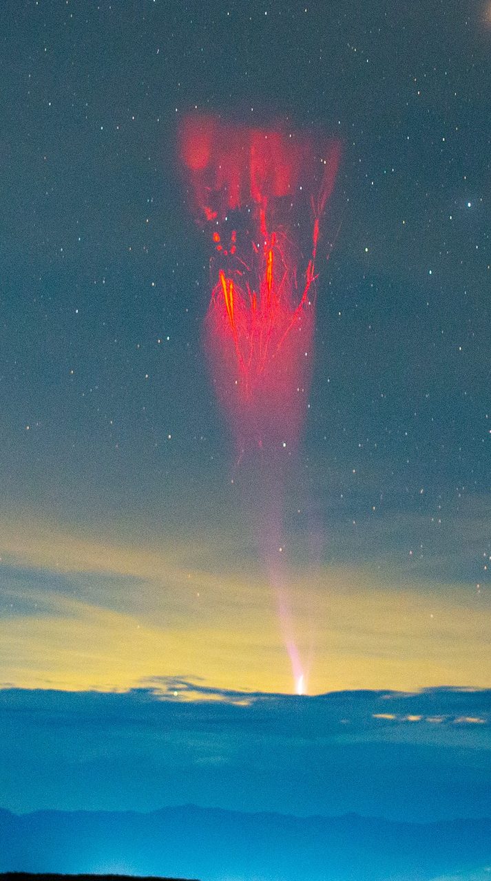 A vivid display of red sprites illuminating the night sky over the Tatacoa Desert landscape.