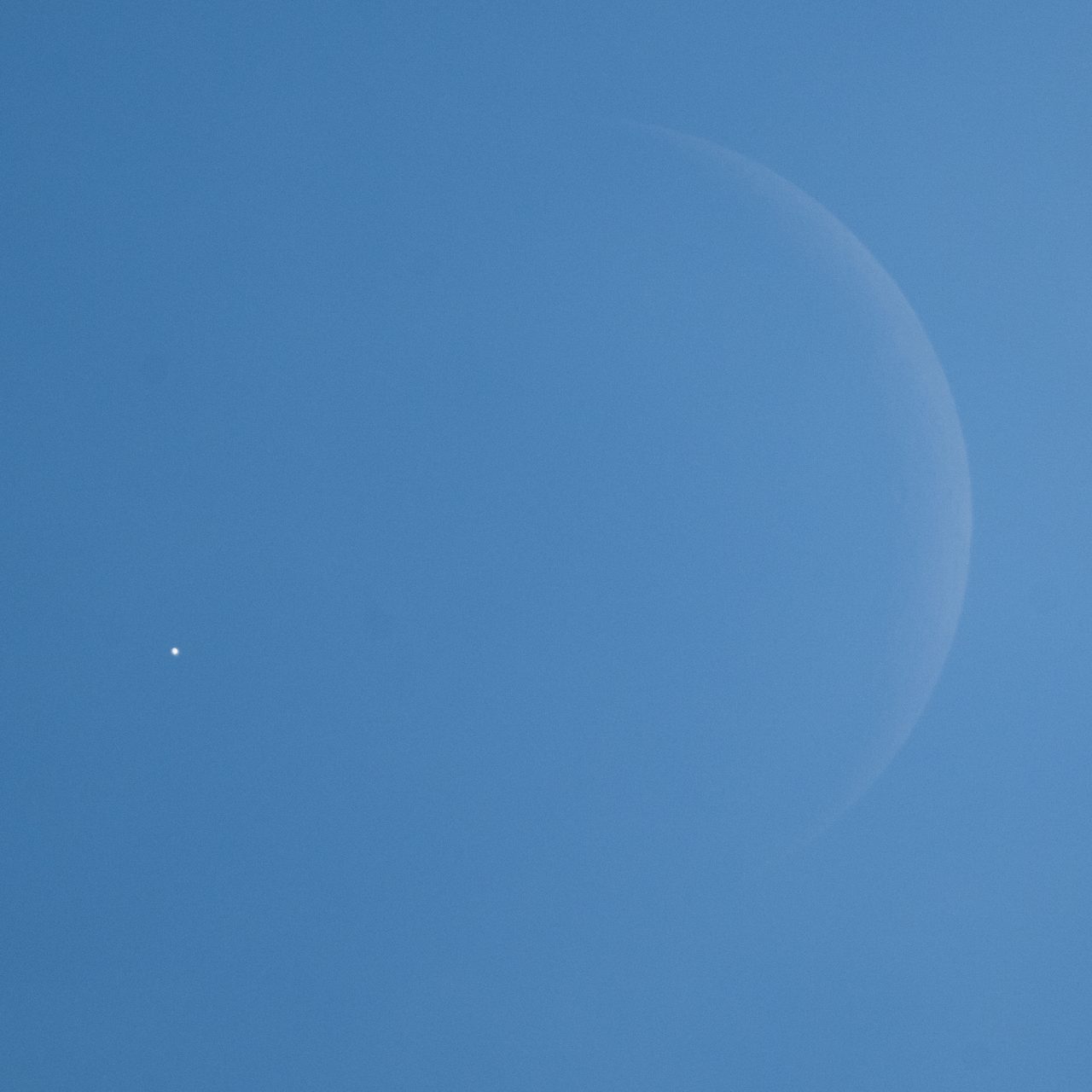 The moon partially obscures Venus in a night sky filled with stars.