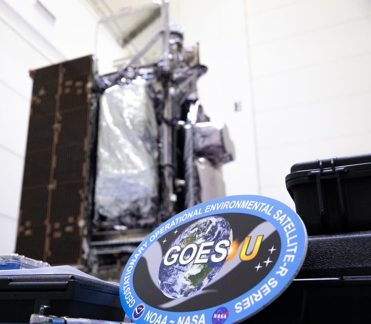 Technicians carefully unbox and position the GOES-U satellite in a vertical stand.