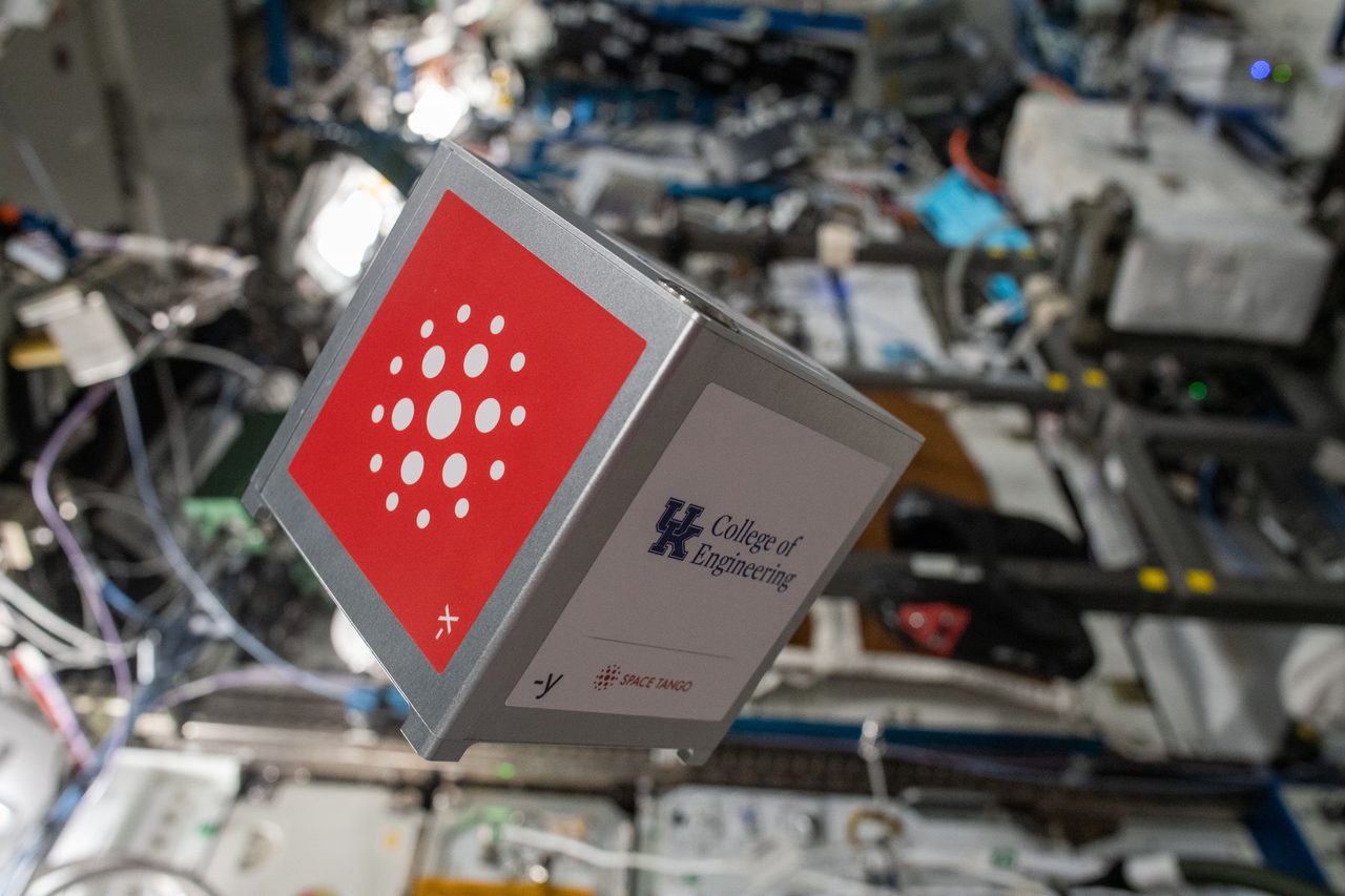 Astronaut removing a card cube from the TangoLab module aboard the International Space Station.