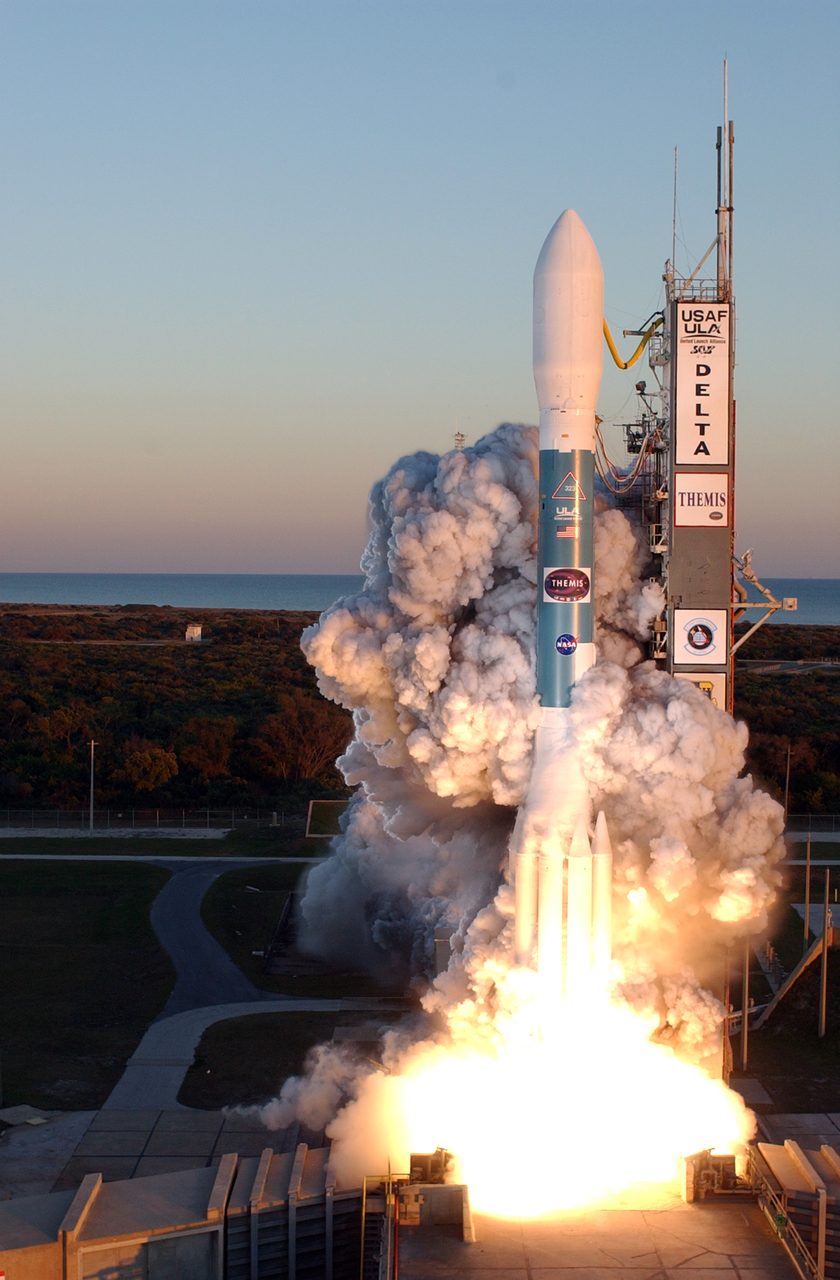 Delta II rocket launching from pad 17B with THEMIS satellite, bright flames and smoke trail visible.