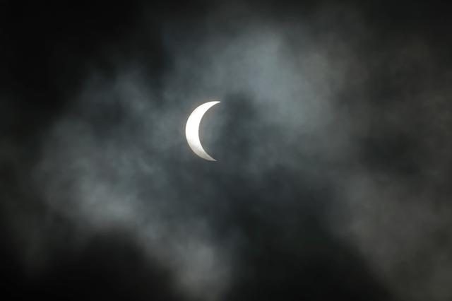 Partial solar eclipse over New Orleans with the Moon covering 85% of the Sun on a cloudy day.
