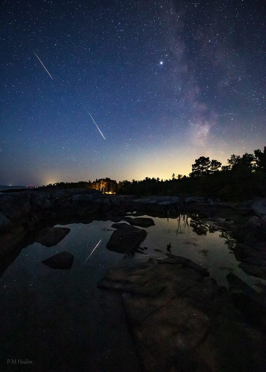 A vibrant display of Perseid meteors streaking across the night sky over a Swedish landscape.