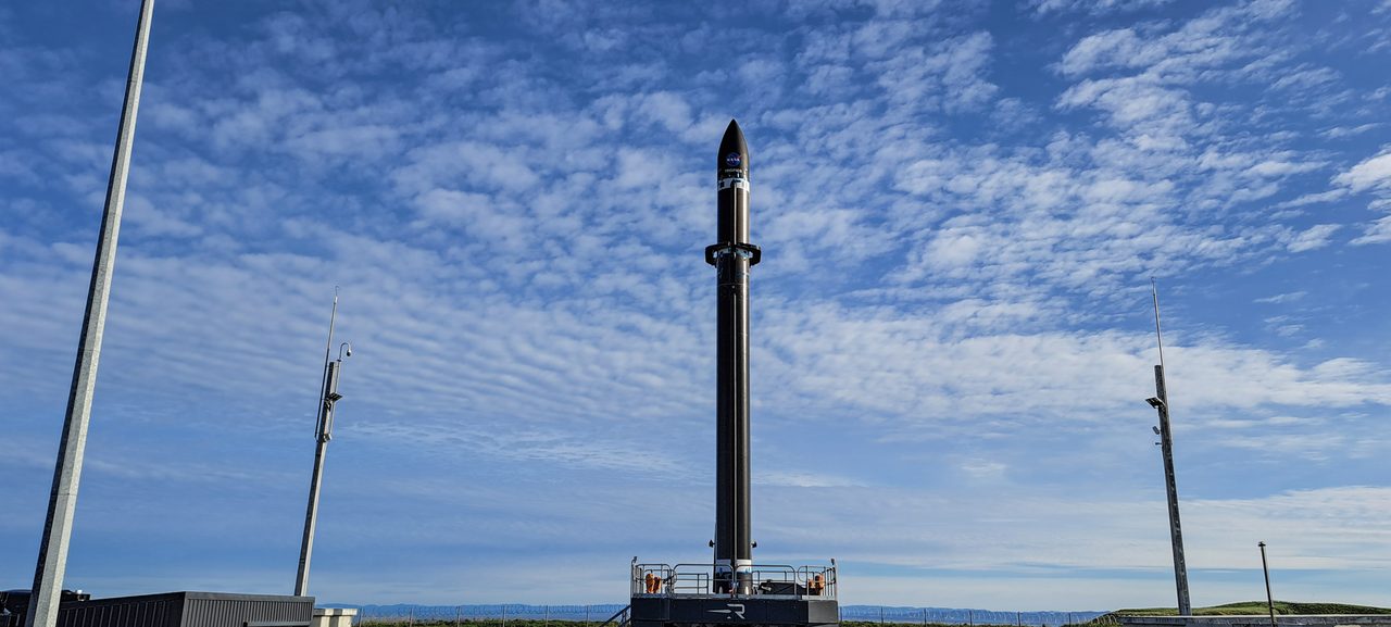 A TROPICS rocket launching into a clear blue sky with white clouds in the background.