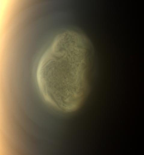 True color image of Titan's south polar vortex with swirling clouds, captured by NASA's Cassini spacecraft in 2012.