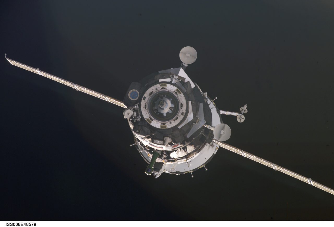 Soyuz TMA-2 spacecraft approaches the International Space Station during Expedition Six, seen from a distance in space.