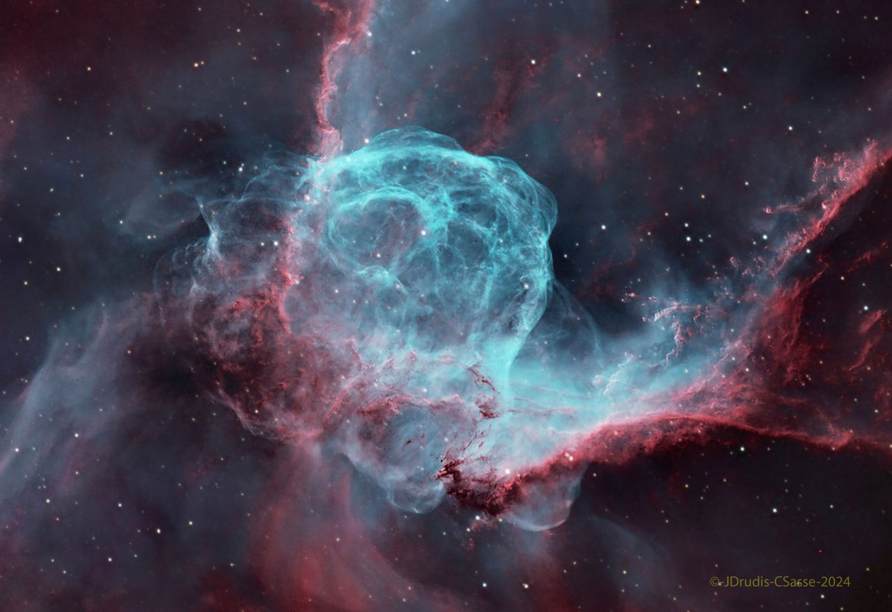 A vibrant nebula resembling a helmet with glowing blue and red hues against a starry backdrop.