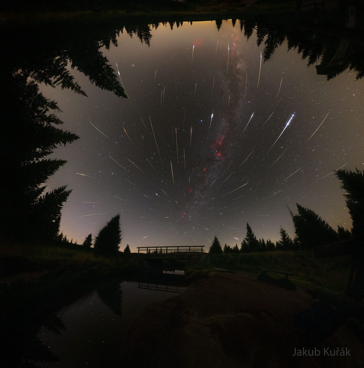 A vibrant meteor shower with streaks of light across a starry night sky, originating from the Perseus constellation.
