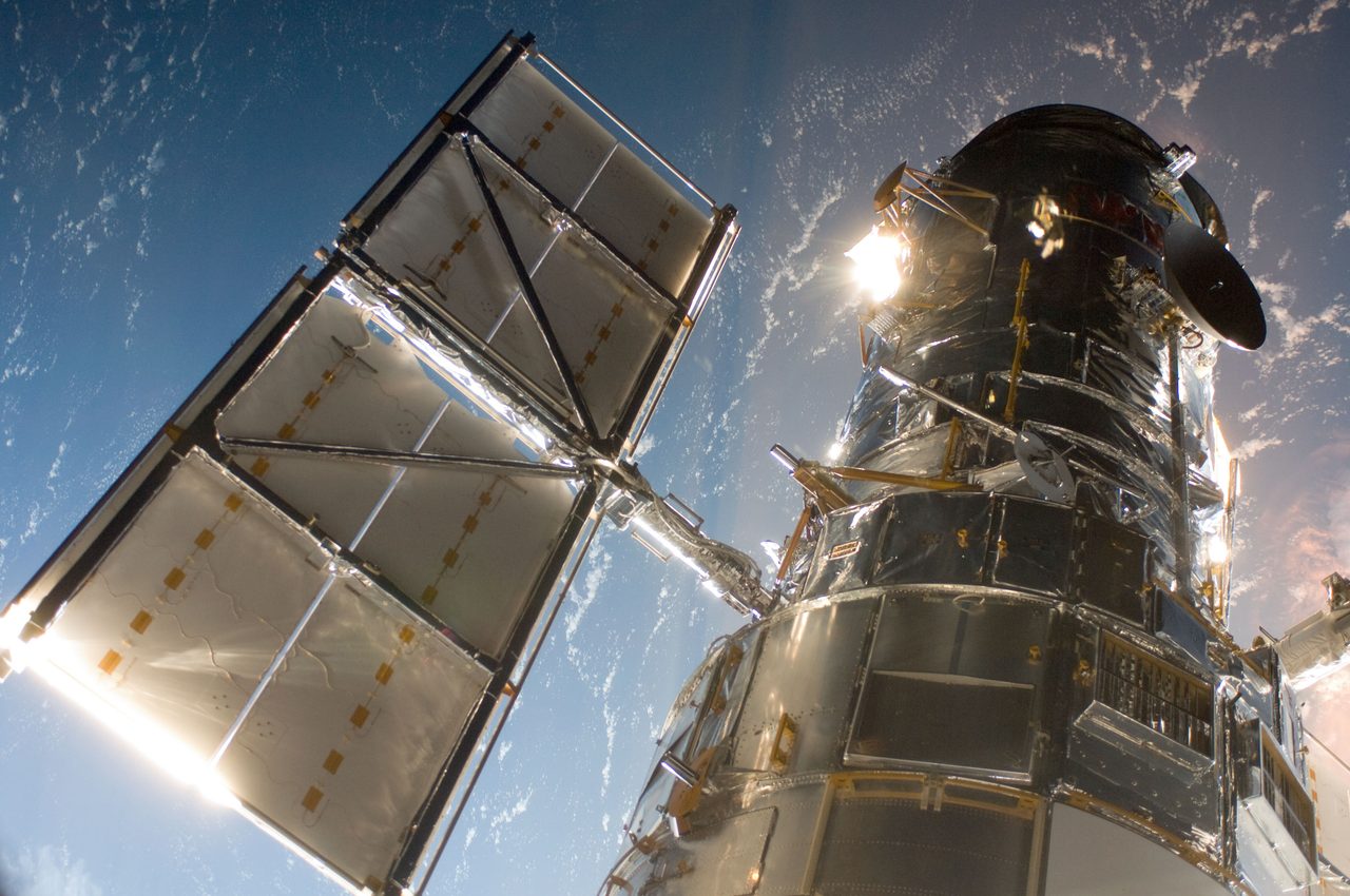 Hubble Space Telescope floating in space against a backdrop of stars, capturing distant galaxies and nebulae.