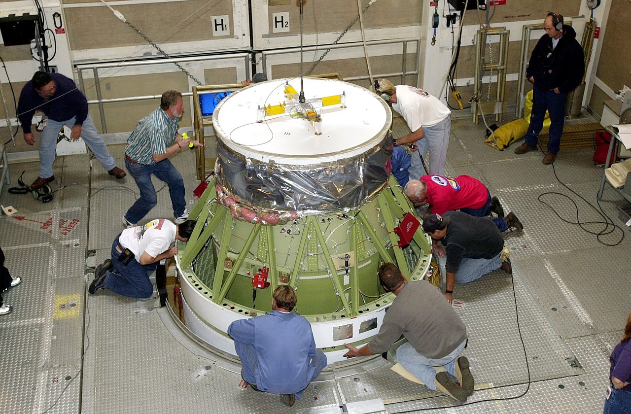 Workers at Vandenberg AFB mating Delta II rocket's stages for Gravity Probe B experiment testing Einstein's relativity.
