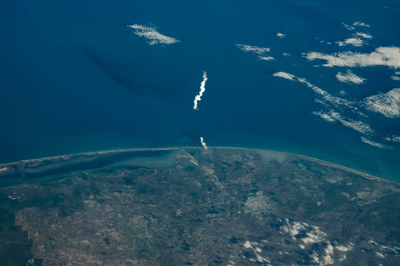Aerial view of SpaceX Starship 6 rocket launching with fiery exhaust, captured from space station window.