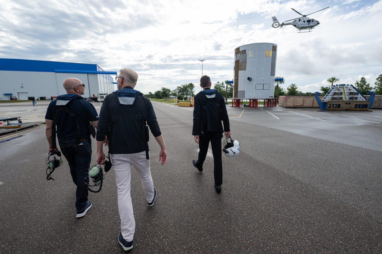 Administrator Isaacman touring Blue Origin facility with engineers and spacecraft models in the background.