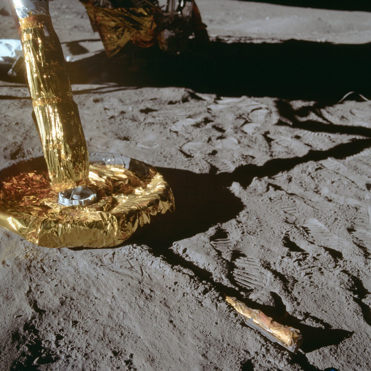 Close-up of Apollo 11 Lunar Module footpad resting on the moon's rocky surface with shadows and dust visible.