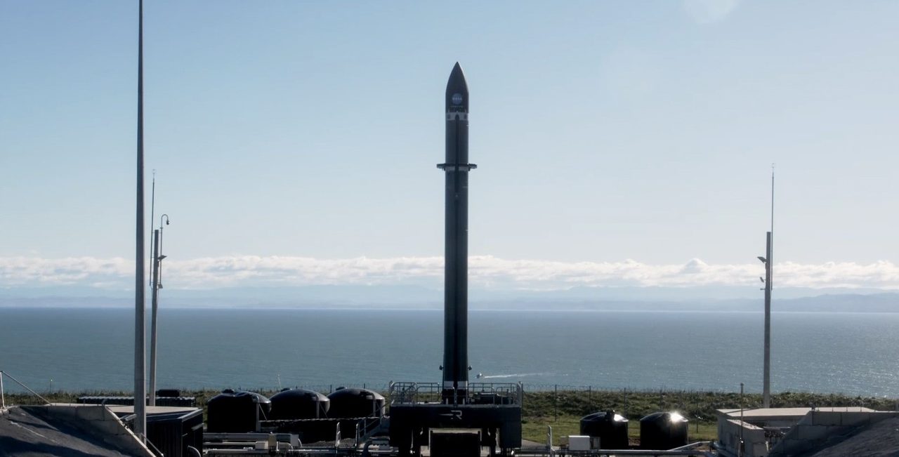 Rocket Lab PREFIRE-1 launch showing rocket ascending against a clear blue sky.