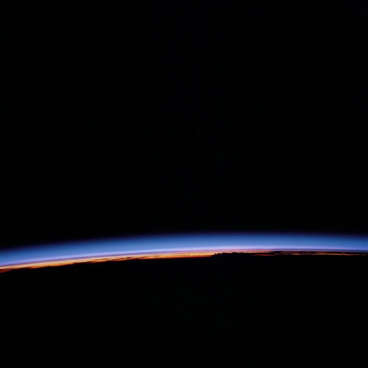 View of Earth's horizon with a glowing sunset casting warm colors across the sky