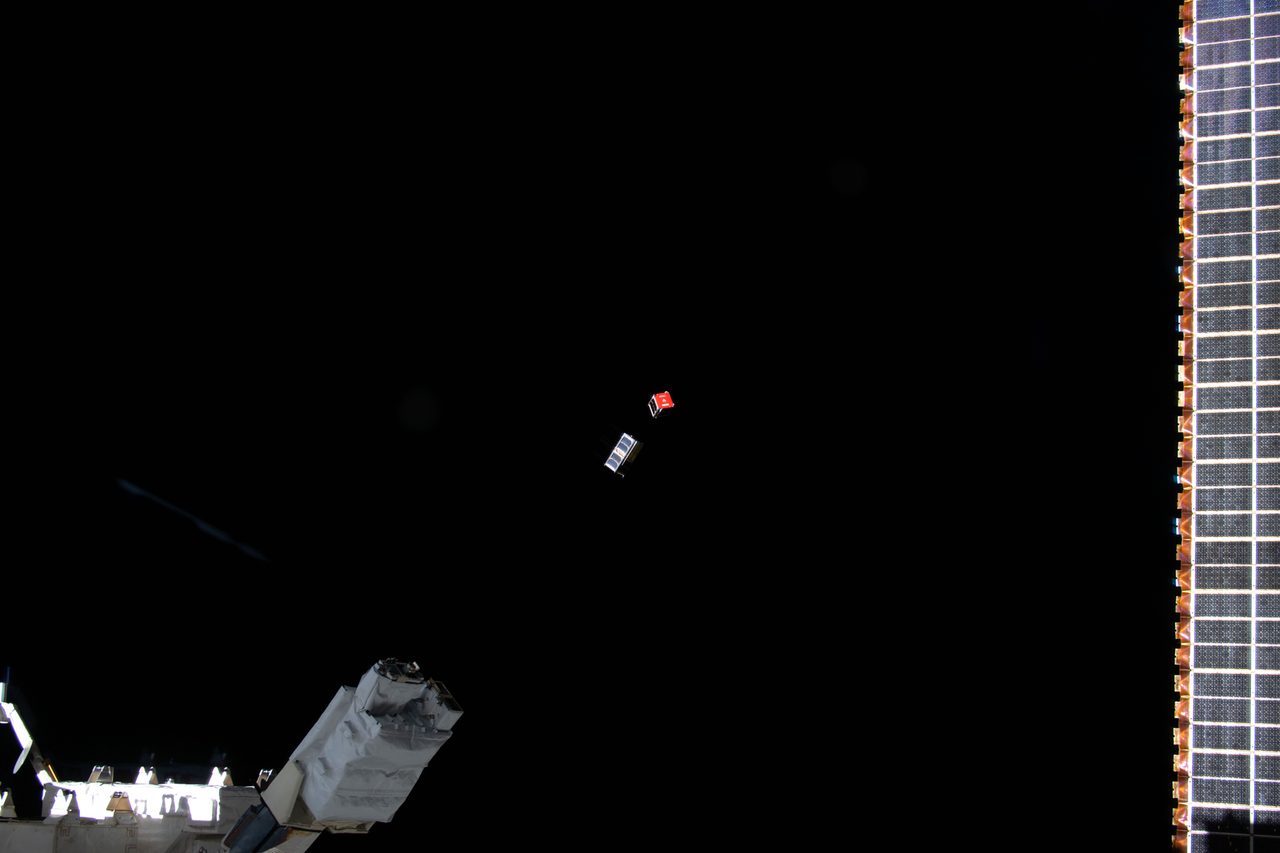 Two CubeSats being released into Earth's orbit from the International Space Station against a backdrop of space.