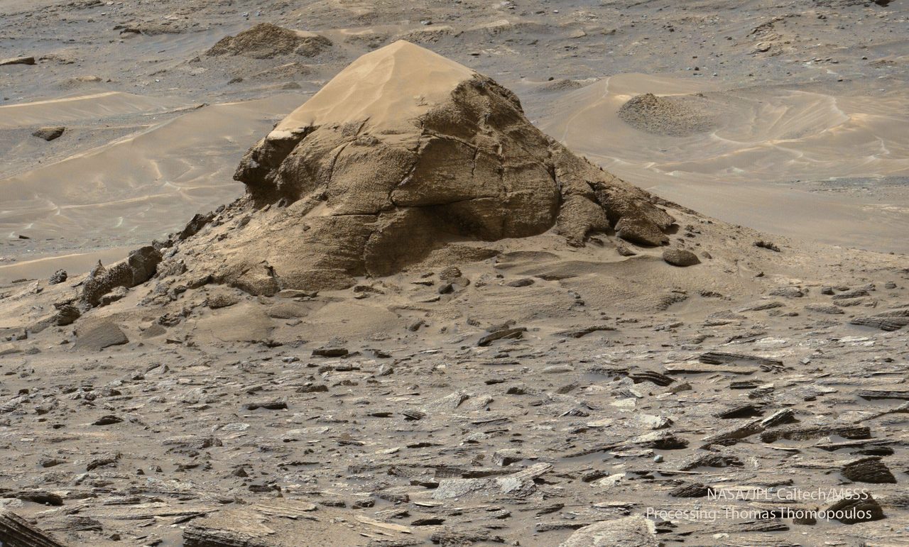 A large, turtle-shaped rock formation on the Martian surface under a clear sky.