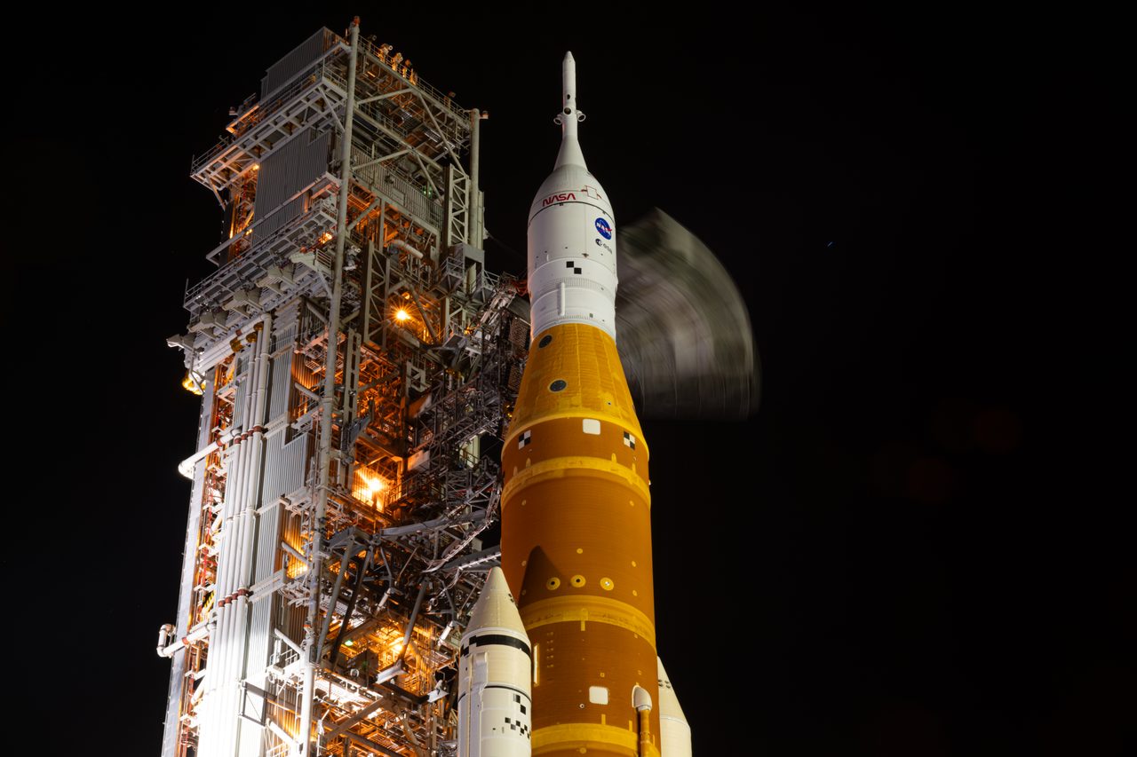 NASA's Artemis II spacecraft being rolled out on a launch pad under clear blue skies.