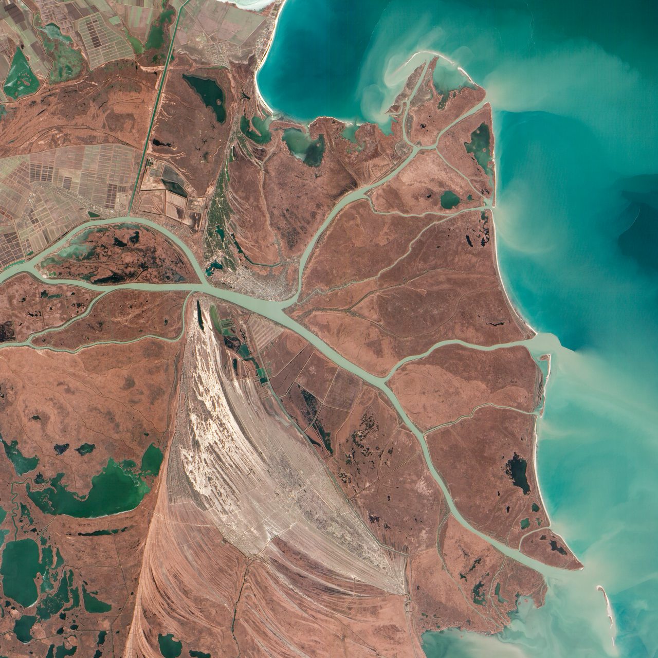 Aerial view of the Danube River merging with the Black Sea under a clear blue sky.