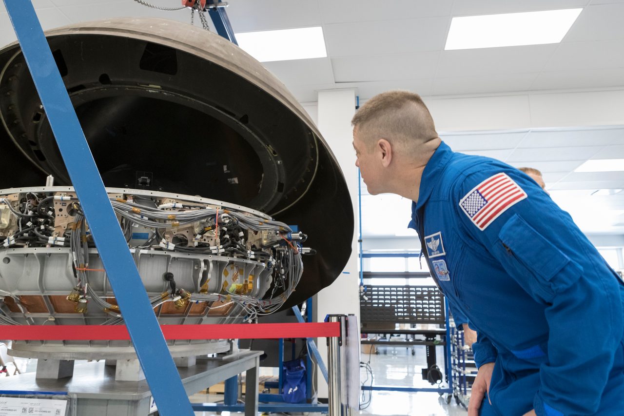 Eric Boe and Bob Behnken exploring the interior of a SpaceX Dragon spacecraft during a guided tour.