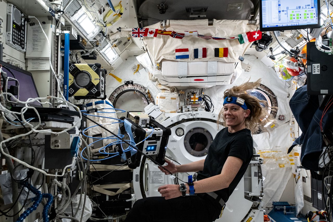 Astronaut Nichole Ayers installing software onto Astrobee robotic free-flyer in space station.
