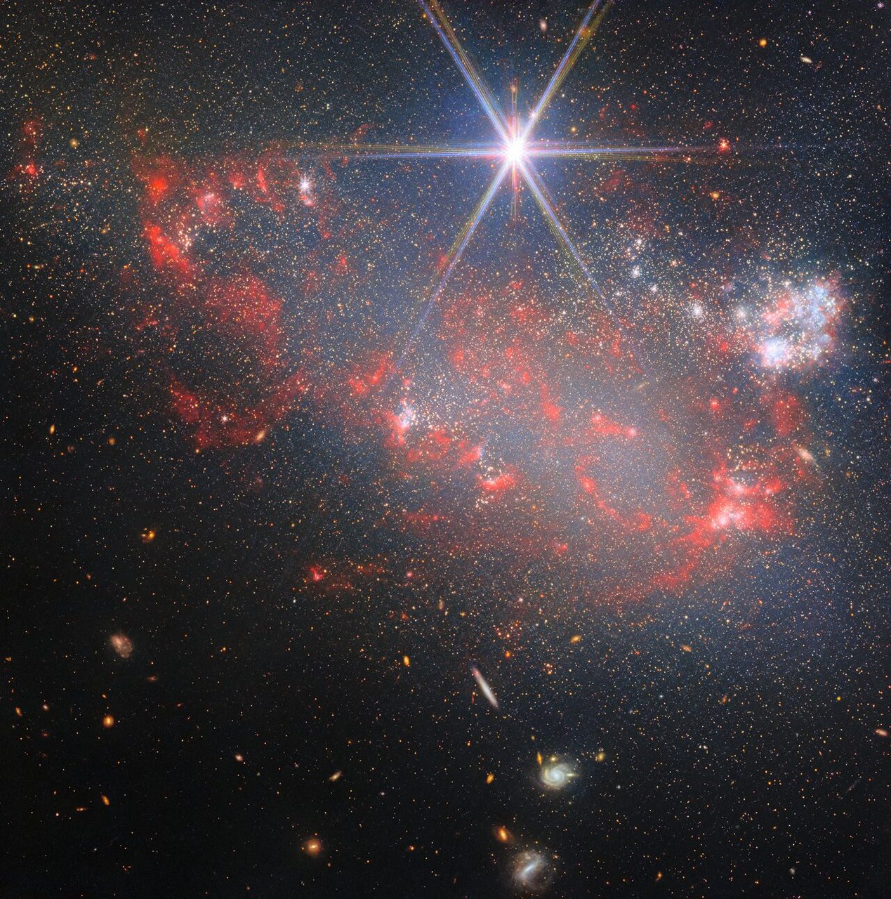 A vibrant cosmic scene with star clusters and irregular clumps against a dark space background.