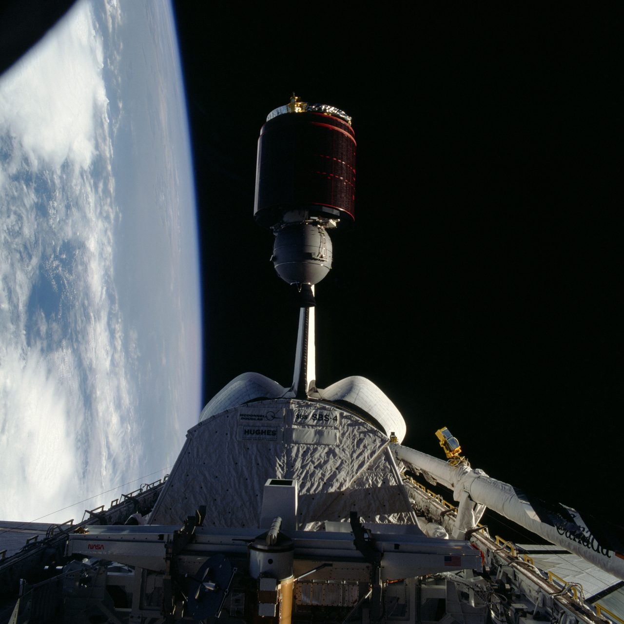 Telstar communications satellite being deployed in space with Earth visible in the background.