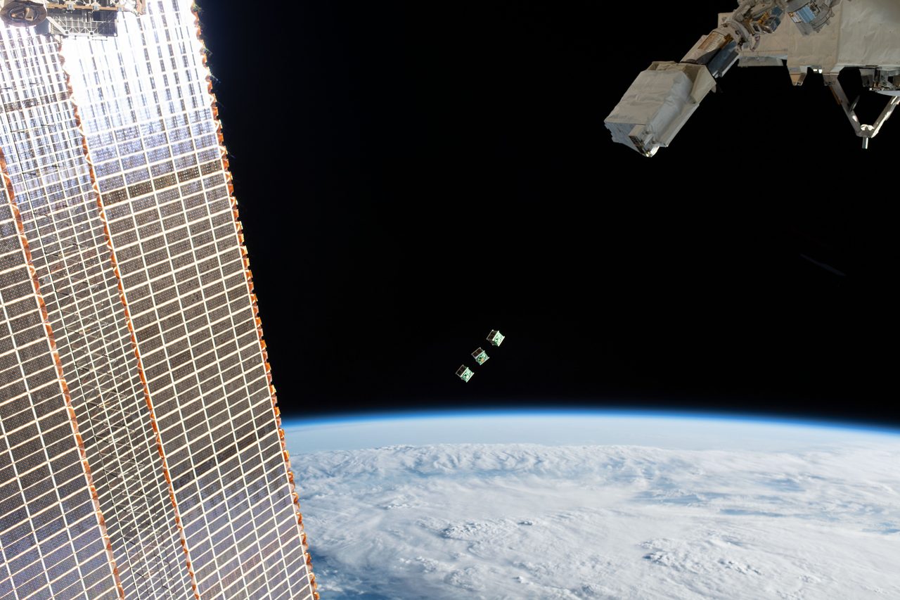 JEM Small Satellite Orbital Deployer #11 releasing micro-satellites into space against a backdrop of Earth.