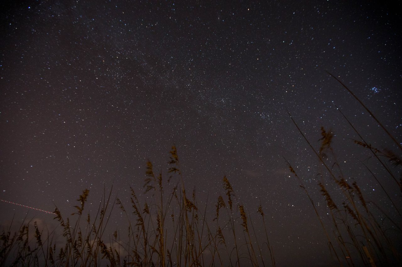 Long exposure photograph of a starry night sky, featuring constellations and a vibrant Milky Way galaxy.