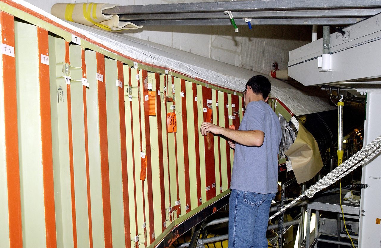 A technician inspects Space Shuttle Atlantis wing spars at Kennedy Space Center, preparing for mission STS-114 to the International Space Station.